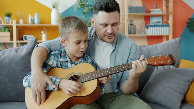 Teacher teaching a child to play guitar during a music lesson